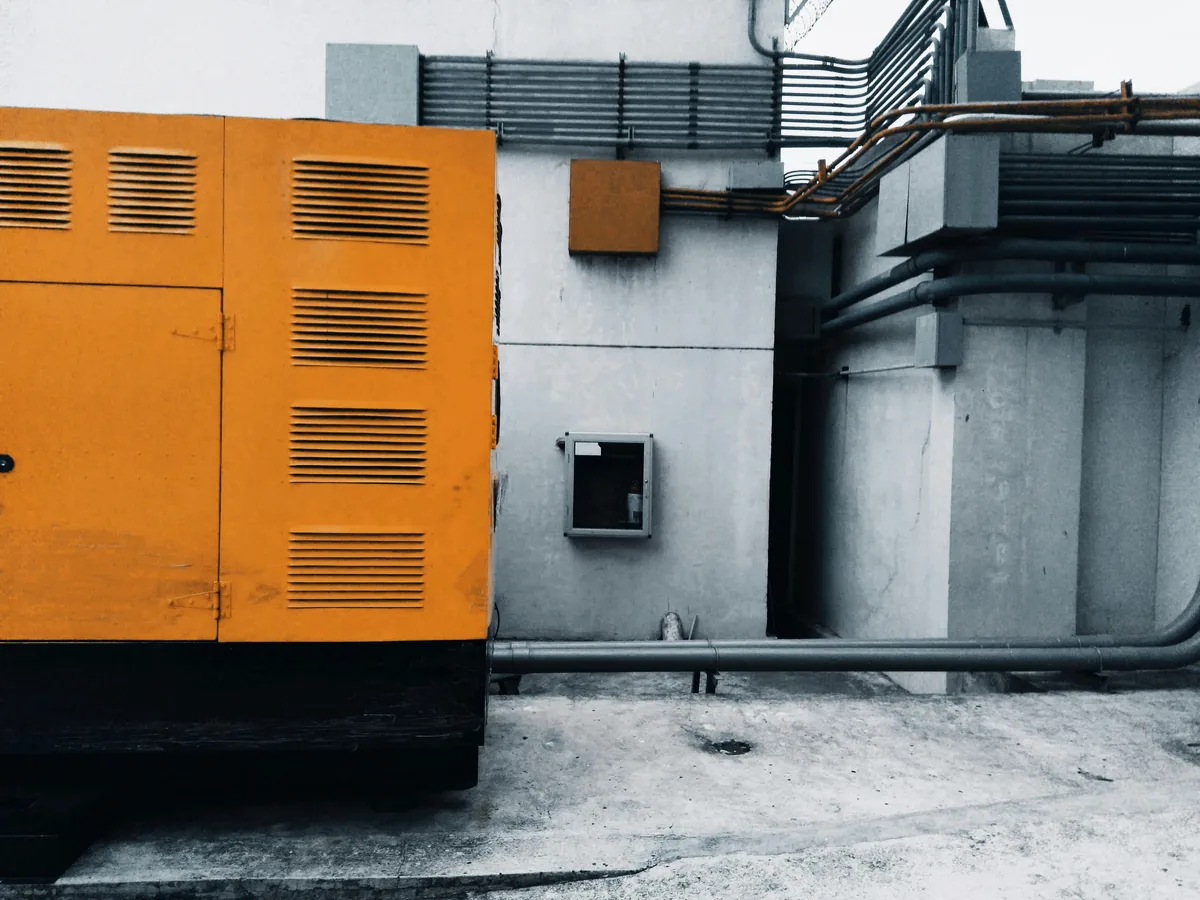 Teknisi memeriksa mesin generator industri untuk perawatan filter udara genset diesel